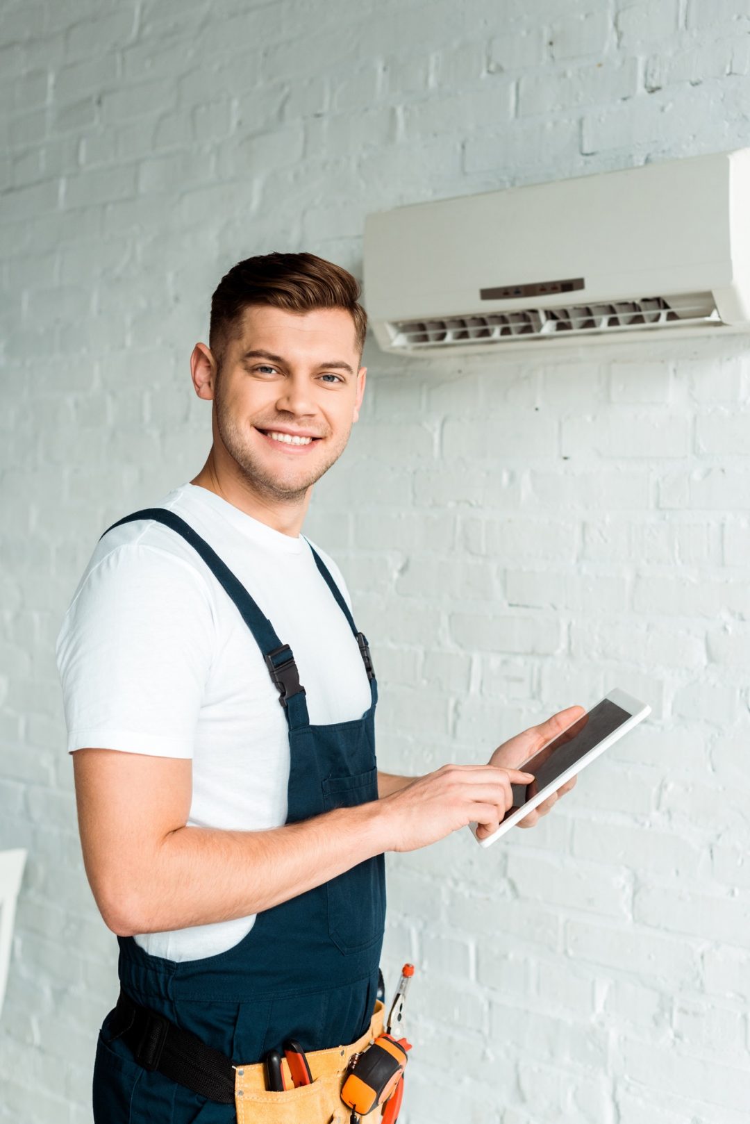 happy installer pointing with finger at digital tablet near air conditioner